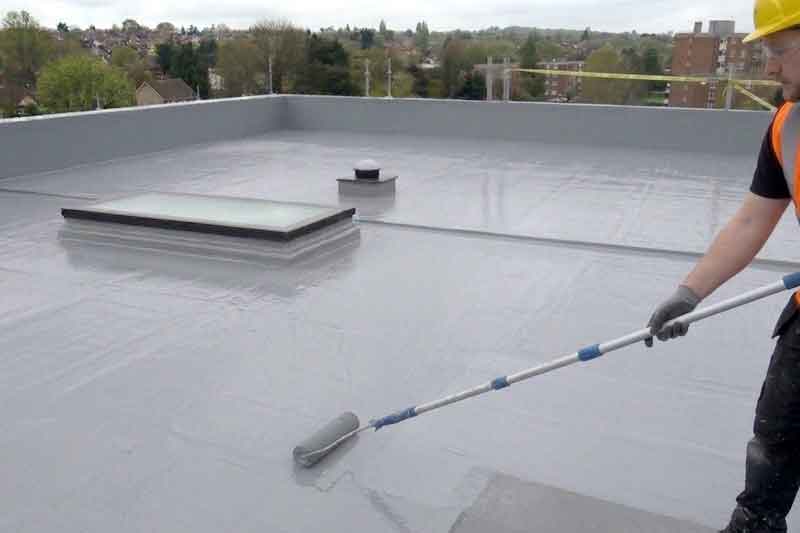 Rolling a liquid rubber for a seamless flat roof repair.